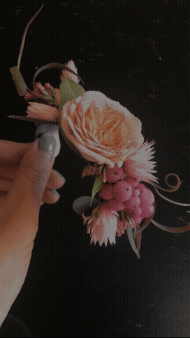 Handcrafted boutonniere with a blush garden rose, pink berries, dried botanical elements, and sculptural accents, created for weddings and elevated event styling.